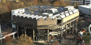 Ein Abrissbagger entfernt die Fassade an der S-Bahn-Seite