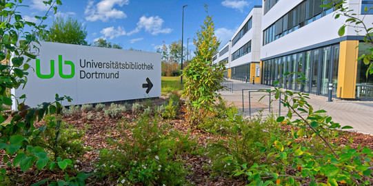 Großes weißes Schild mit Pfeil weist zum Gebäude Sebrathweg 7