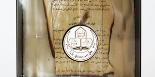 An den Rändern verbranntes Buchfragment mit arabischer Schrift