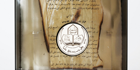 Buchfragment aus dem Bestand der zerstörten Bibliothek der Universität Mossul (Irak) An den Rändern verbranntes Buchfragment mit arabischer Schrift