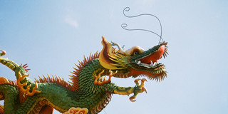A dragon statue on a building against blue sky