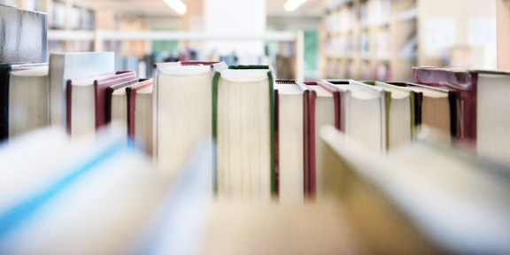 Public library bookshelf with books from behind