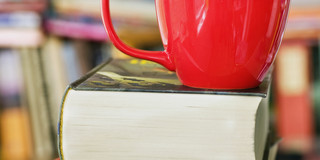 Bücherstapel mit rotem Kaffeebecher darauf