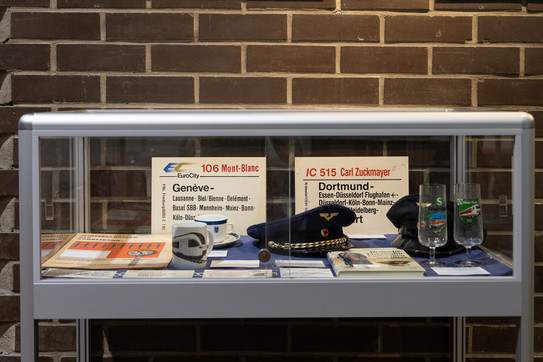 Showcase of the exhibition "Locomotives and people" Showcase with train run plates, glasses, cups and railroad caps