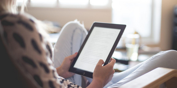 Woman reading e-book A Woman is sitting in an armchair and reading an e-book