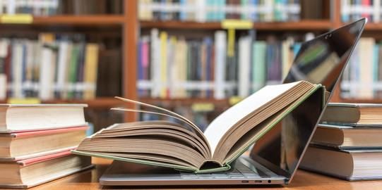 Open book in laptop Opened book is in opened laptop and next to other books