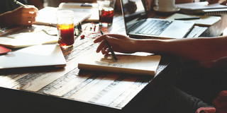 Writers sitting at a table with laptops, notebooks and drinks