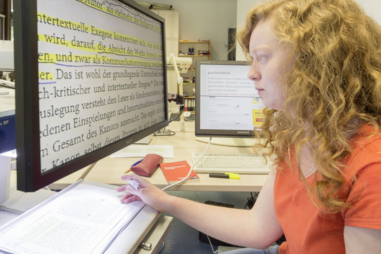 Sehgeschädigte Studentin arbeitet an Text in Vergrößerung am Monitor