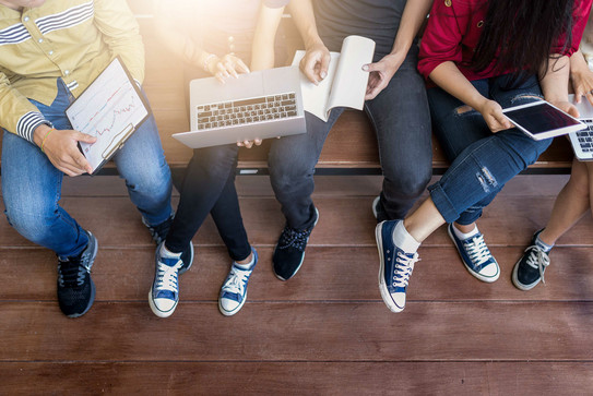 The legs of five young people learning with tablet and laptop