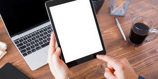 A man with a tablet, a smartphone and a laptop sits at a table 