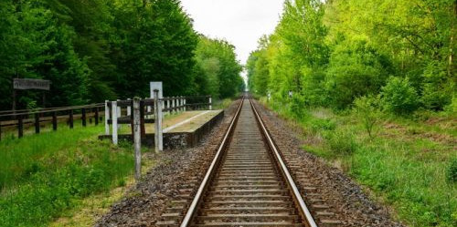 Eisenbahnschienen Eisenbahnschienen zwischen grünen Bäumen verlaufen in der Ferne
