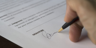 Vertrag wird mit schwarzem Stift unterschrieben