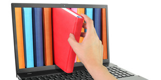 Laptop computer with colored books, one of which is pulled out