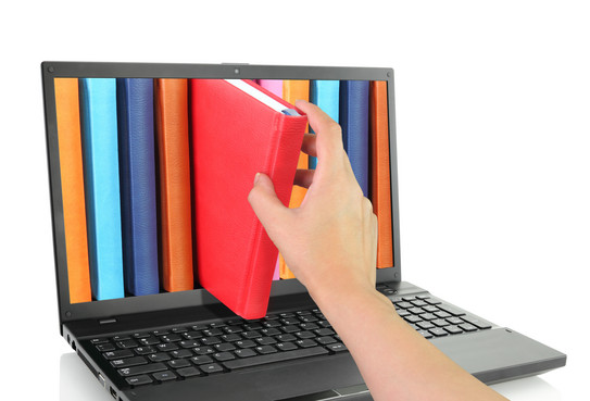 Laptop mit bunten Büchern, von denen eins herausgezogen wird