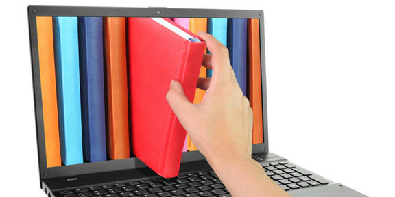 Laptop computer with colored books, one of which is pulled out