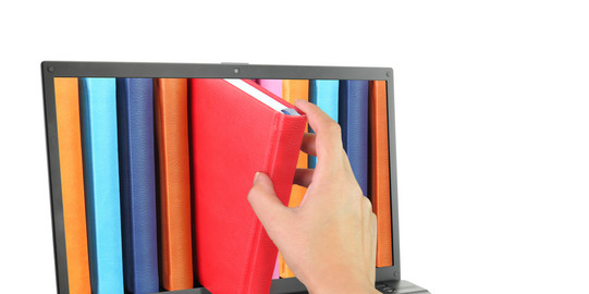 Laptop computer with colored books, one of which is pulled out