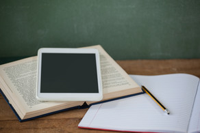 A tablet, a book and a notebook lie on a table