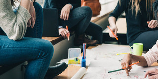 Eine Lerngruppe aus 4 jungen Menschen diskutiert an einem Tisch