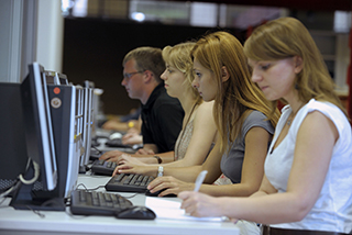 Studentinnen sitzen vor Bildschirmen in der Bibliothek