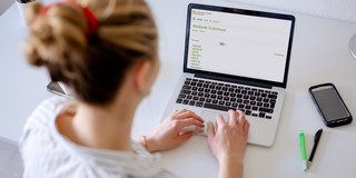 Foto einer Frau, die auf einen Laptop blickt.