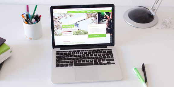 Arbeitsplatz mit Laptop Arbeitsplatz am Schreibtisch, mit eingeschaltetem Laptop und Stiften.