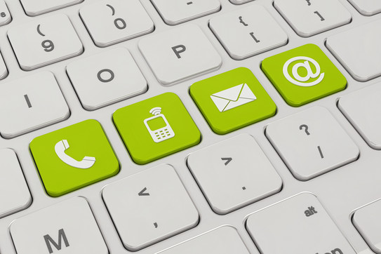 A white keyboard with four green keys. On the green keys are symbols like a telephone, a cell phone, an envelope and an „@“