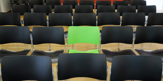 Row of seats in black and green A green chair in the middle of black chairs