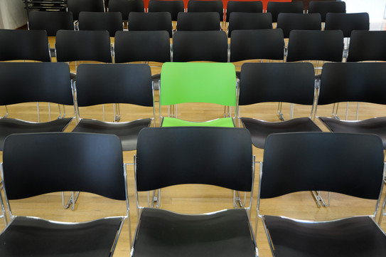 A green chair in the middle of black chairs