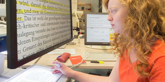 Student analyzing text A student sits at a computer reading a text in large print.