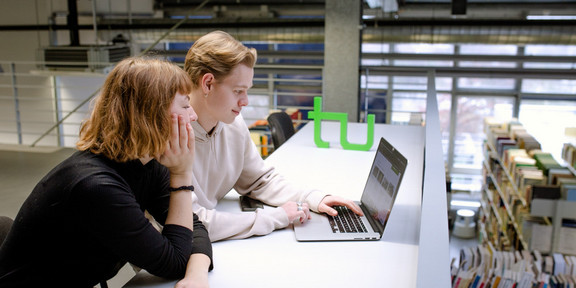 Two students sitting at the table in the library and working.