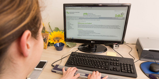 A blind student is learning at a computer using a special keyboard.